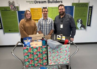 Two men and a woman with a cart of animal donations