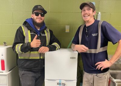 Two men standing with donated fridge